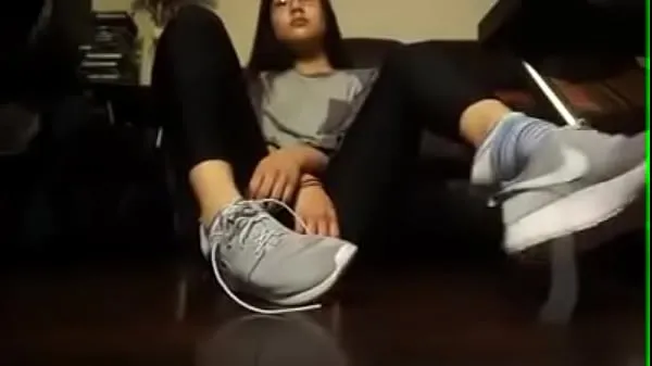 Stora Asian girl takes off her tennis shoes and socks klipprör